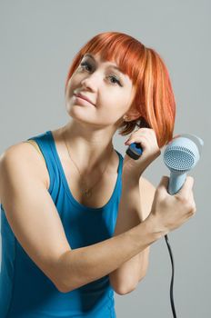 Woman with hairdryer and a hairbrush taking care of her red hair