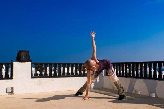 Attractive redhair woman practicing Vinyasa yoga outdoors