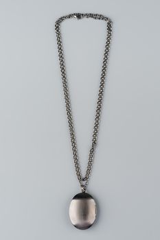 Silver necklace with pendant shot on gray background