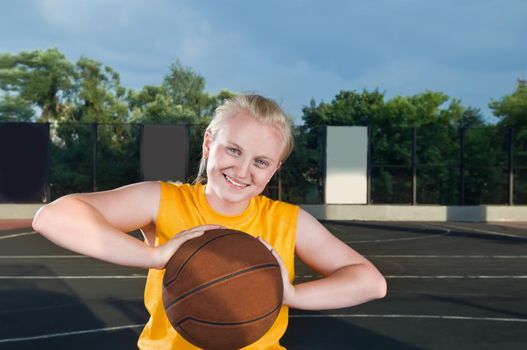Happy smiling girl with basketball at the street court