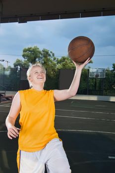 Teenage girl wearing yellow shooting basketball at the street playground