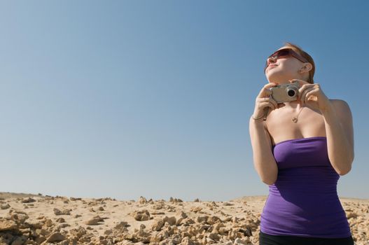 Girl with compact camera taking photos at the desert