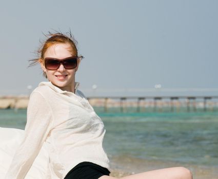 Beautiful red woman taking sun baths by the ocean