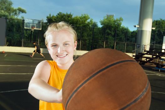 Teenage girl wearing yellow holding basketball at the street playground