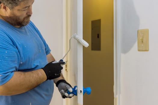 Close up of painter hands with gloves painting the door frame using hand roller on worker home restoration