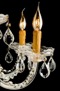 Closeup view of Contemporary glass chandelier candles isolated over black background
