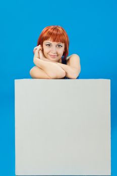 Beautiful red girl sitting behind blank board ready for your text