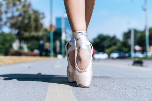 The feet of a Peruvian ballet dancer on an asphalt floor in the street