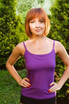 Beautiful healthy-looking red woman posing outdoors in a green park