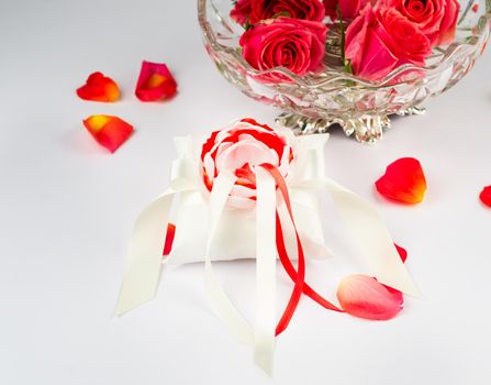 Exquisite pillow for wedding rings on gray background with rose petals