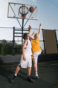 Two teenagers playing streetball - girl shooting the ball