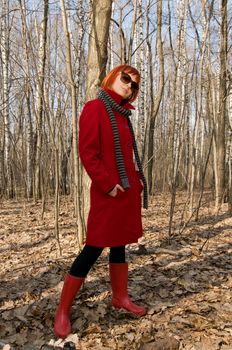 Beautiful girl wearing red coat and boots walking in the early spring