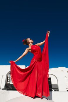 Attractive flamenco dancer wearing traditional red dress with flower in her hair