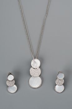 Silver necklace with earrings on grey background
