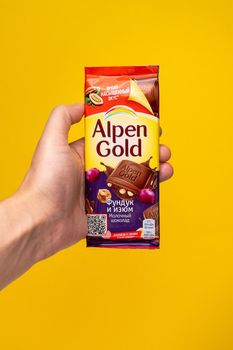 Tyumen, Russia-May 25, 2021: Milk chocolate with nuts and raisins Alpen Gold. Vertical photo