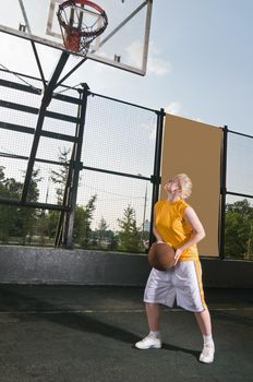 Teenage girl with basketball at the street playground