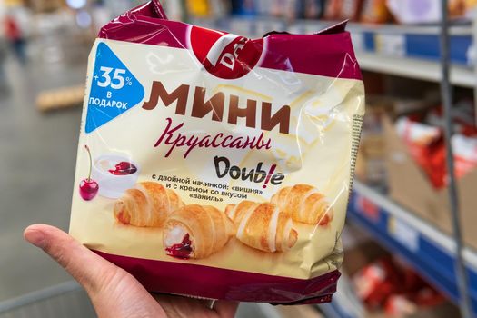 Tyumen, Russia-june 08, 2021: 7days croissant with a grocery hypermarket in the buyer's hand. Selective focus
