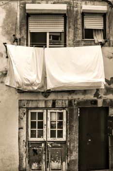 Old facade of typical Lisbon house with hanging clothes in clothesline. Monochrome photography