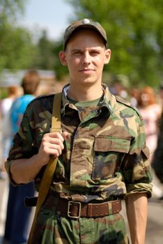 Young soldier poses with some civilians in the blurred out-of-focus background