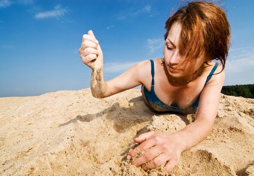 Red haired girl playing with the sand at the beach