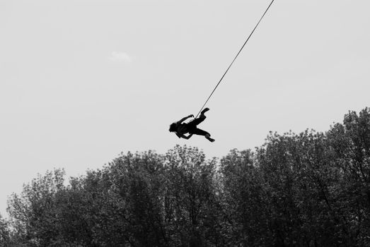 Silhouette of a girl jumping with a rope from the bridge