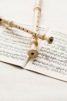 Two block-flutes placed over textbook with musical notes. High key