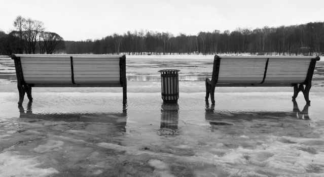 Two benches in the park during a thaw