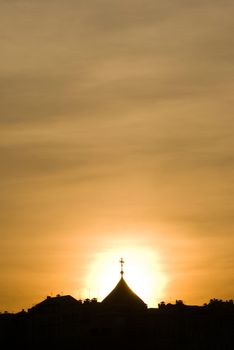 Church dome is backlit with a sunset sky