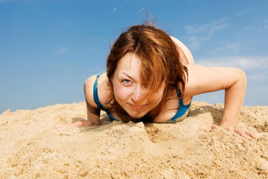 Red haired girl playing with the sand at the beach