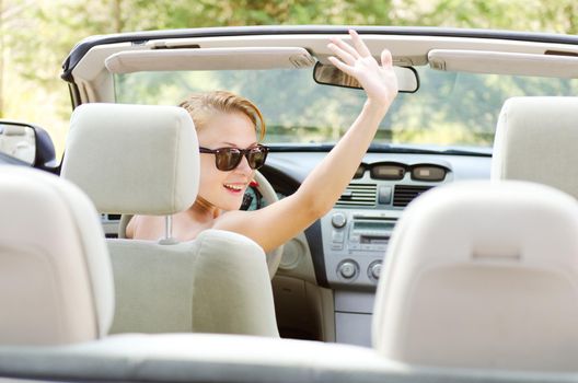 Young red woman greeting her friends while driving