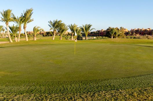 View on golf field with flag at sunset