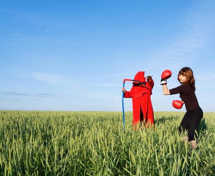 Healthy sporty girl and spooky figure in red hood with a scythe