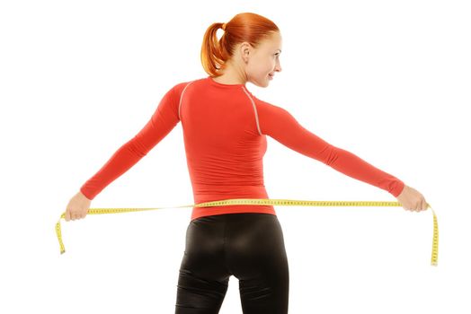 Beautiful slim red fit woman holding measuring tape to her waist over white background