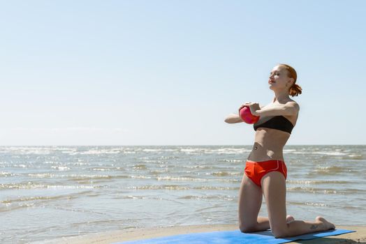 Beautiful woman practicing fitness by the sea on a sunny day