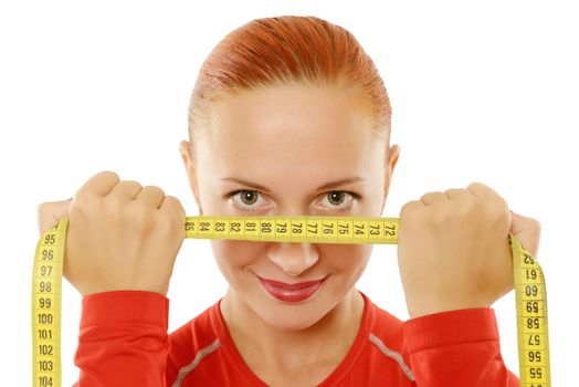 Beautiful slim red fit woman holding measuring tape to her face over white background