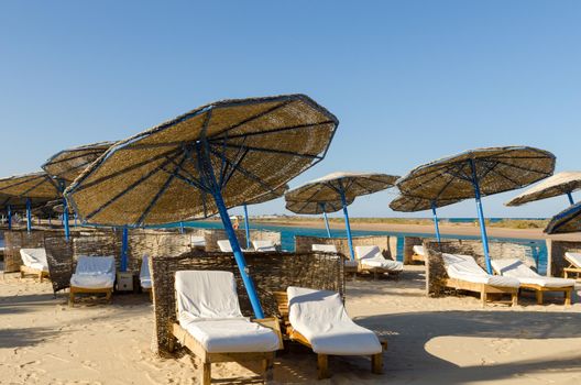 Sunbeds with umbrellas on the beach with nobody around