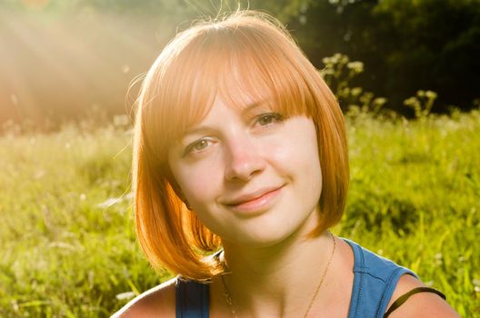 Beautiful red haired woman portrait outdoors on a summer day