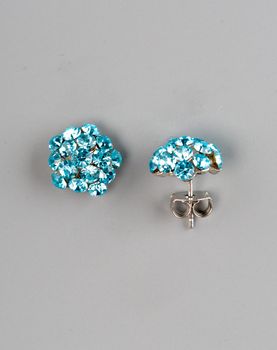 Pair of earrings with gems on grey background