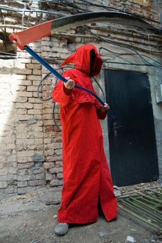 Spooky person in red hood threatning with his scythe