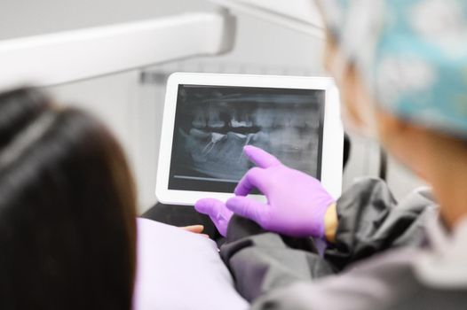 Health care concept - Female dentist showing tablet computer to woman patient at dental clinic office. High quality photo