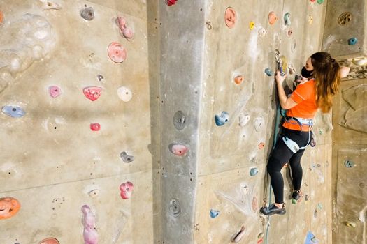 Young fit woman climbing on indoor rock wall. Aerial cinematic footage . High quality photo.