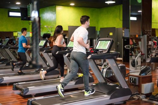 Group of people running on treadmills in modern sport gym. High quality photo