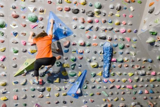 Young fit woman climbing on indoor rock wall. Aerial cinematic footage . High quality photo.