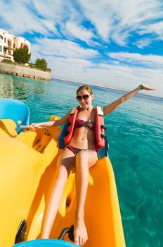 Cheerful young woman riding catamaran at the sea