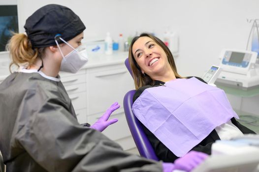 Young female patient visiting dentist office.Beautiful woman sitting at dental chair with open mouth during oral checkup while doctor working at teeth. High quality photo