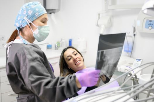 Female dentist pointing at patient's X-ray image in dental office. High quality photo