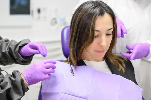 Medical secretary preparing dental treatment putting on dental bib on patient. High quality photo