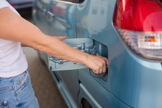 Woman refueling car with gasoline at self-service gas station