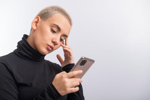 Young caucasian woman with short hair uses a smartphone on a white background