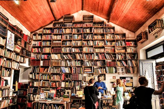 Obidos, Lisbon, Portugal- June 3, 2018: People buying books in an Old bookstore with selves full of books in Obidos, Portugal.